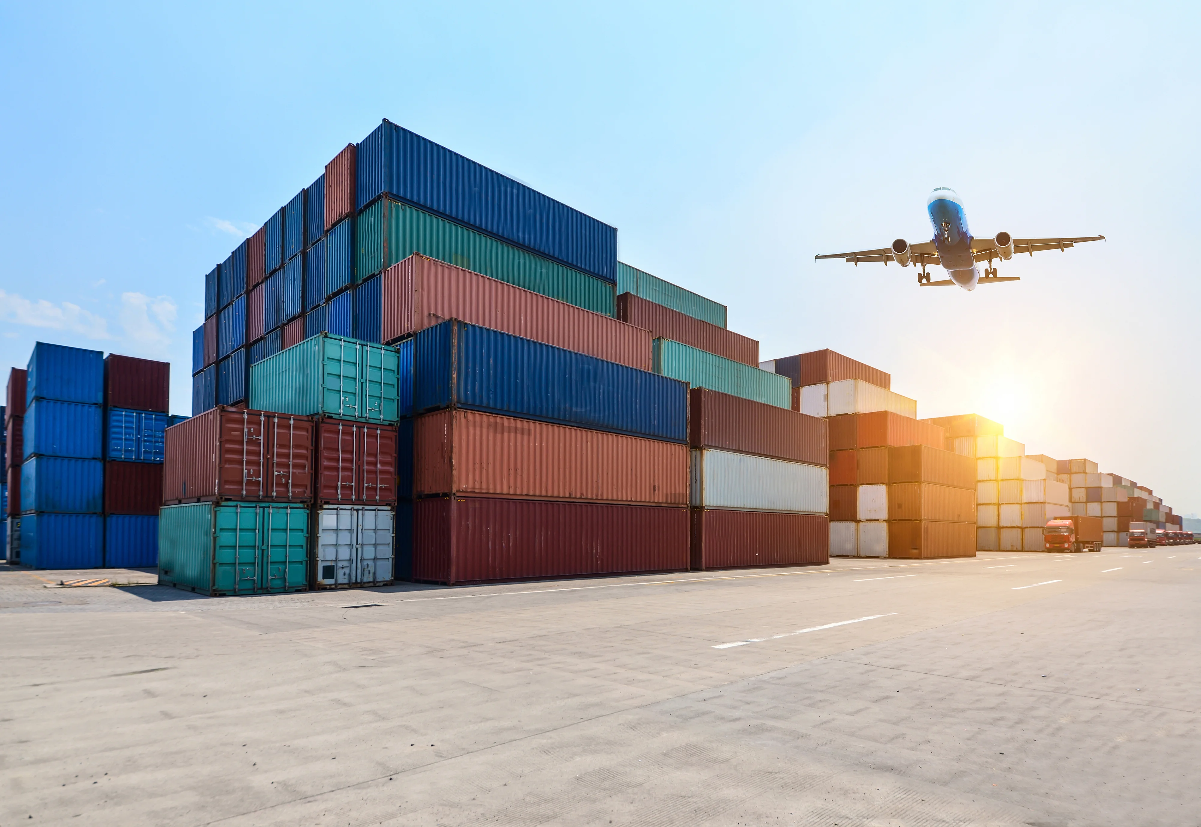 Cargo containers at a freight terminal with aircraft in the background